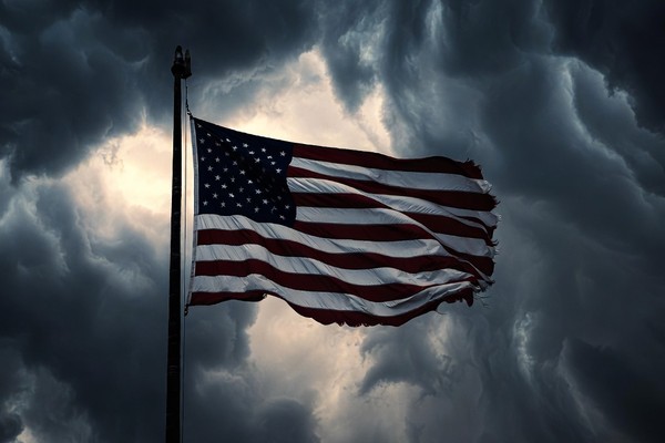 A weathered American flag against a dark storm sky